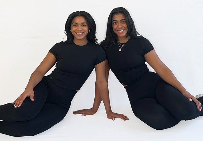 The twins are posing while sitting.